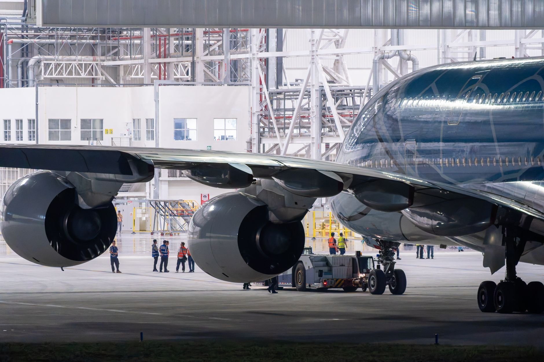 Close-up of an airplane engine inside a maintenance hangar with crew staff